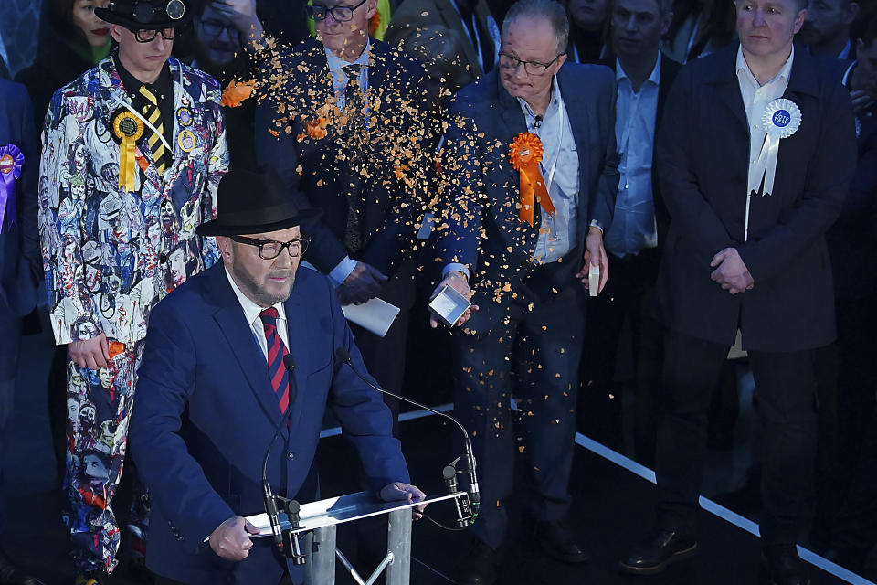 George Galloway, foreground, has confetti thrown at him by Just Stop Oil protestors as he gives a speech after being declared winner in the Rochdale by-election, which was triggered after the death of Labour MP Sir Tony Lloyd, in the town of Rochdale, England Thursday, Feb. 29, 2024. (Peter Byrne/PA via AP)