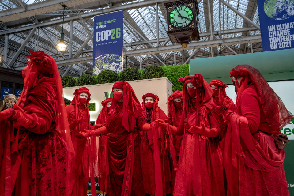 Activistas climáticos en la estación central de Glasgow en Glasgow, Escocia, el lunes 1 de noviembre de 2021. Al fondo, se ven pancartas de la cumbre COP26 de las Naciones Unidas. (Andrew Testa/The New York Times)
