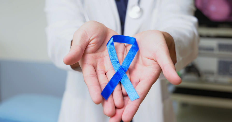 Colorectal cancer is the third leading cause of cancer deaths amongst men and women. (Photo via Getty Images) close up asian male doctor is holding blue ribbon on hands to disseminate colorectal cancer prevention and control