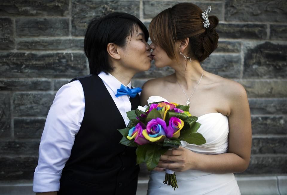 A couple kiss as they pose for a picture before taking part in "The Celebration of Love", a grand wedding where over 100 LGBT couples will get married, at Casa Loma in Toronto