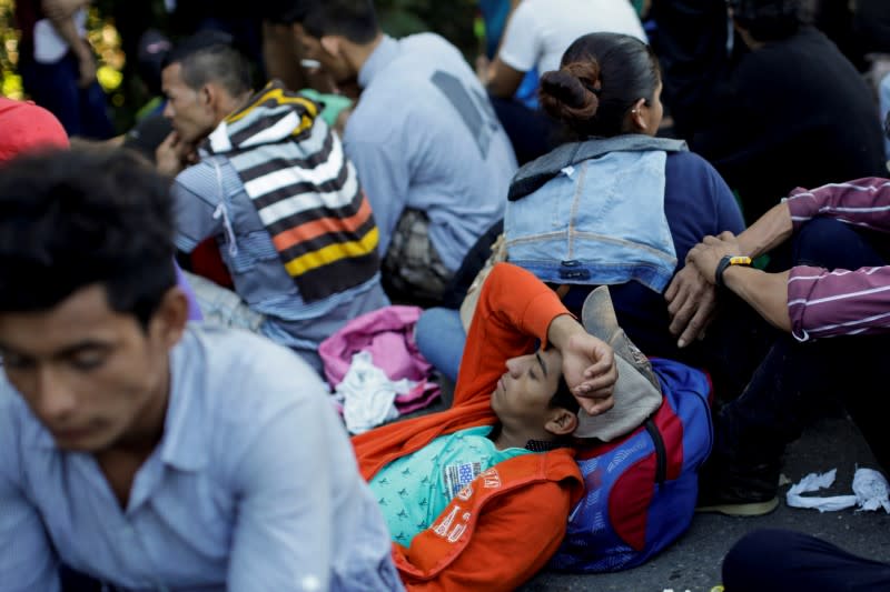 Migrantes, principalmente de Centroamérica y marchando en una caravana, descansan en una carretera cerca de Ignacio Zaragoza, Chiapas