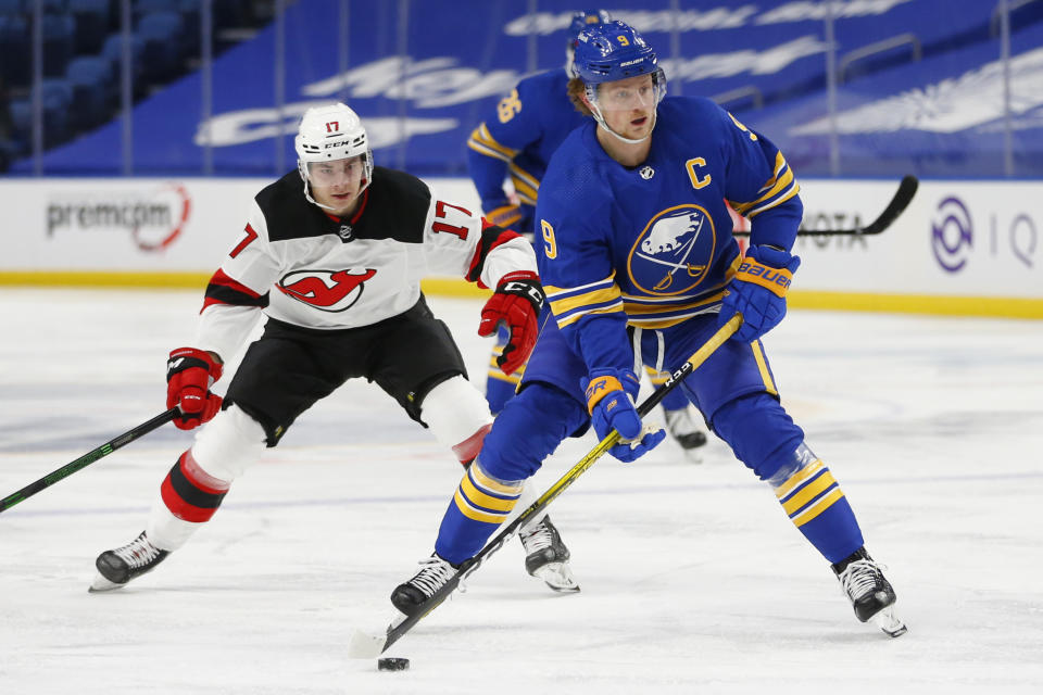 Buffalo Sabres forward Jack Eichel (9) carries the puck past New Jersey Devils forward Yegor Sharangovich (17) during the second period of an NHL hockey game Saturday, Jan. 30, 2021, in Buffalo, N.Y. (AP Photo/Jeffrey T. Barnes)