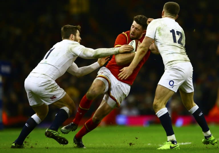 Wales' wing Alex Cuthbert (C) is tackled by England's wing Elliot Daly (L) and England's centre Owen Farrell (R) during the Six Nations international rugby union match between Wales and England on February 11, 2017