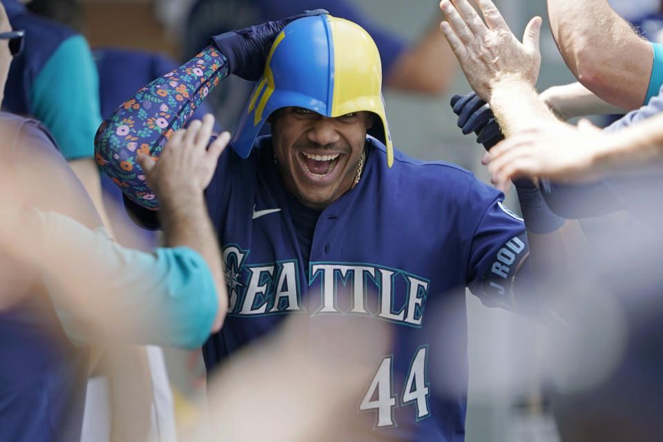 Seattle Mariners' Julio Rodriguez wears a helmet as he is greeted in the dugout after his three-run home run against the Texas Rangers during the seventh inning of a baseball game Wednesday, July 27, 2022, in Seattle. (AP Photo/Ted S. Warren)