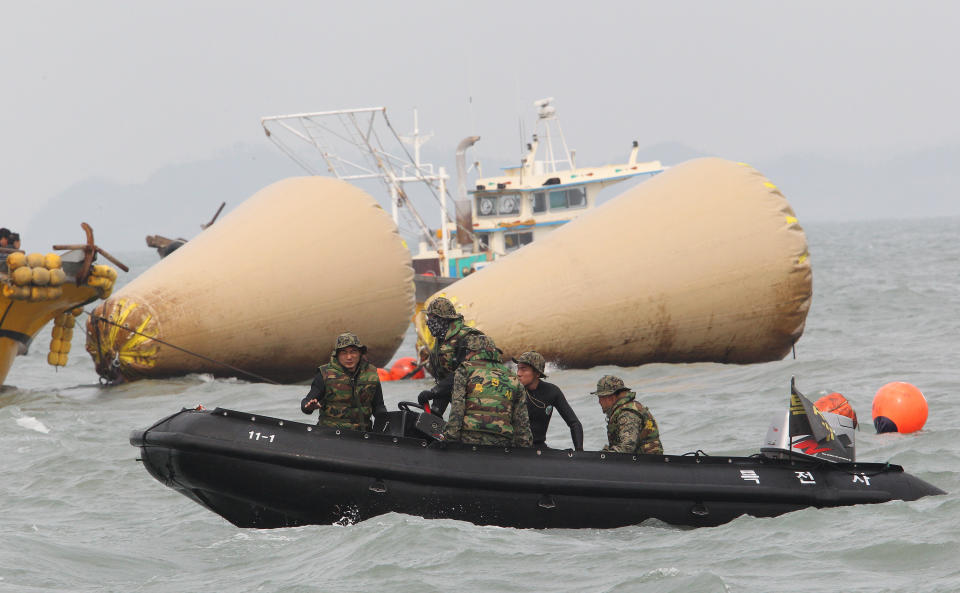 South Korean rescue team members work to rescue passengers believed to have been trapped in the sunken ferry Sewol near the buoys which were installed to mark the vessel in the water off the southern coast near Jindo, South Korea, Monday, April 21, 2014. Divers continued the grim work of recovering bodies from inside the sunken South Korean ferry Monday, securing a new entryway into the wreck, as a newly released transcript showed the ship was crippled by confusion and indecision well after it began listing. The transcript suggests that the chaos may have added to a death toll that could eventually exceed 300. (AP Photo/Ahn Young-joon)