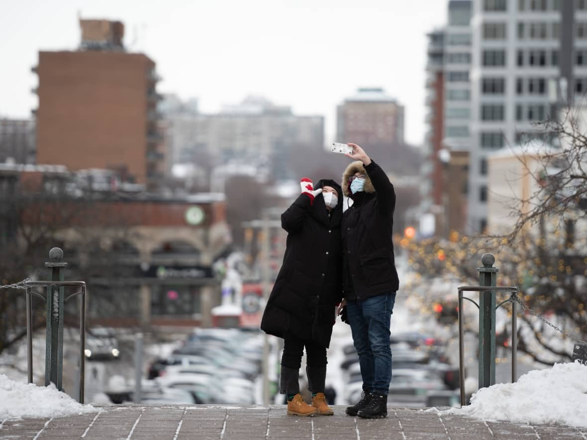 Whether it was returning to perform on-stage or preparing to move into a new home, five Ottawa personalities are reflecting on significant moments from their lives in 2022. Pictured here are two people taking a Christmas Day selfie overlooking the ByWard Market. (The Canadian Press - image credit)