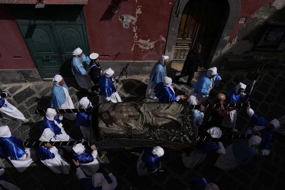 Faithful carry an 18th century wooden Christ before the start of a procession the in Procida Island, Italy, Friday, March 29, 2024. Italy is known for the religious processions that take over towns big and small when Catholic feast days are celebrated throughout the year. But even in a country where public displays of popular piety are a centuries-old tradition, Procida's Holy Week commemorations stand out. (AP Photo/Alessandra Tarantino)