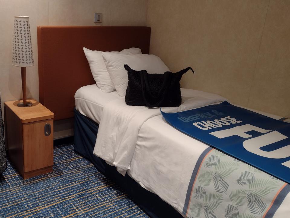 A twin-size cruise bed with a small nightstand and a suitcase next to it.