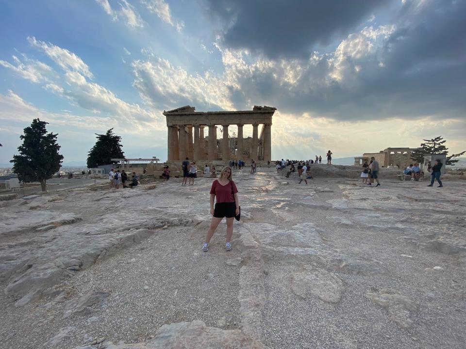 writer standing in front of a ruin in greece