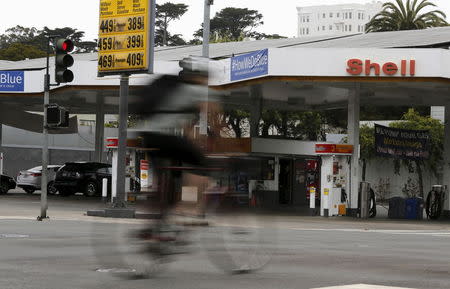 A cyclist rides past a sign showing the prices of gas at a filling station in San Francisco, California July 22, 2015. REUTERS/Robert Galbraith