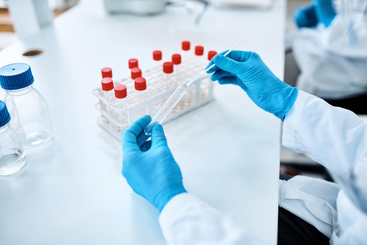 Closeup shot of an unrecognisable scientist holding a sampling swab and test tube in a lab