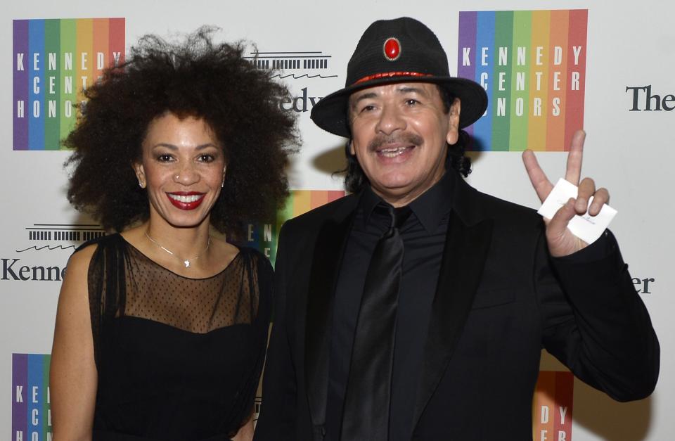 Mexican American rock guitarist and multi-Grammy Award winner Carlos Santana, 66, a 2013 Kennedy Center Honoree, gestures as he and his wife Cindy Blackman arrive at the U.S. State Department for a gala dinner, in Washington