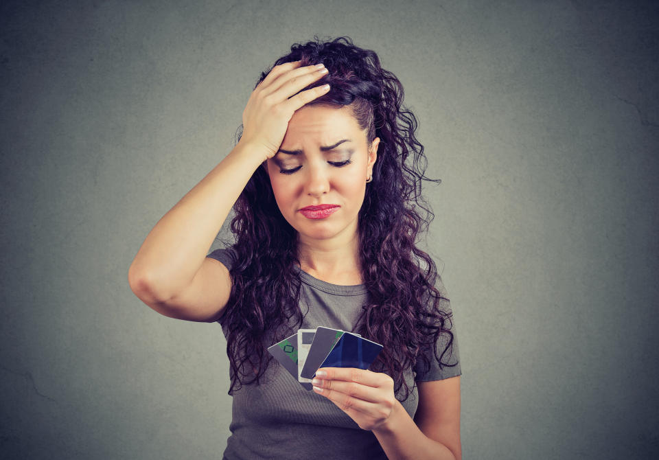 Sad stressed woman looking at too many credit cards.