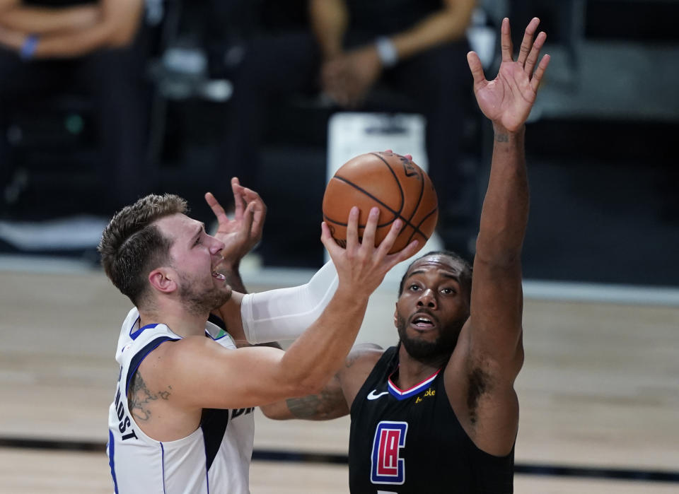 Los Angeles Clippers' Kawhi Leonard (2) fouls Dallas Mavericks' Luka Doncic (77) during the second half of an NBA first round playoff game Sunday, Aug. 30, 2020, in Lake Buena Vista, Fla. (AP Photo/Ashley Landis)