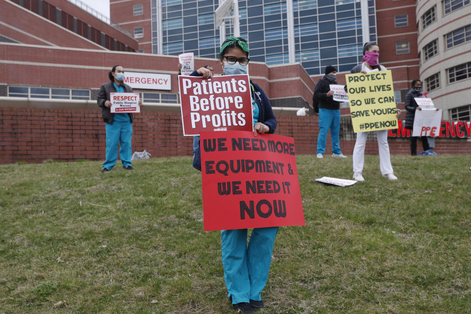 Nurses stand on a hill outside the emergency entrance to Jacobi Medical Center in the Bronx borough of New York, Saturday, March 28, 2020, as they demonstrate with members of the New York Nursing Association in support of obtaining an adequate supply of personal protective equipment for those treating coronavirus patients. A member of the New York nursing community died earlier in the week at another New York hospital. The city leads the nation in the number of coronavirus cases. Nurses say they are having to reuse their protective equipment endangering patients and themselves. (AP Photo/Kathy Willens)