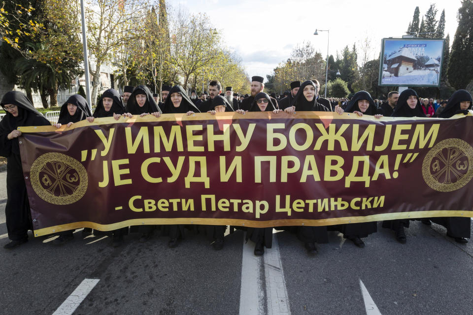 Serbian Orthodox Church clergy in Montenegro march and hold a banner reading: ''Judgment and Justice are in God's name'' as they protest the planned adoption of a religious law that they say will pave the way to strip the church of its property, in Podgorica, Montenegro, Tuesday, Dec. 24, 2019. Montenegro's pro-Western president has accused the church of promoting pro-Serb policies in Montenegro and seeking to undermine the country's statehood since it split from Serbia in 2006. (AP Photo/Risto Bozovic)