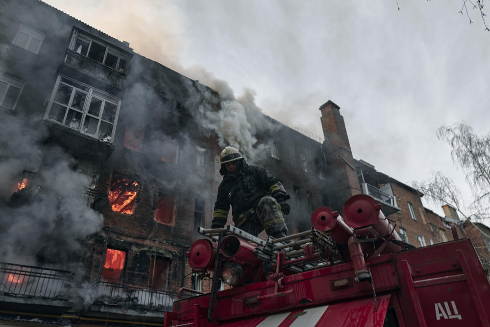 Emergency workers put out the fire after Russian shelling hit an apartment building in Bakhmut, Donetsk region, Ukraine, Wednesday, Dec. 7, 2022. (AP Photo/LIBKOS)
