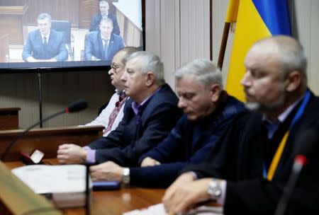 Jury members and a judge (L-R) attend the trial of former riot police force members suspected of killing participants of the 2014 anti-government and pro-European Union mass protests, as Ukraine's former President Viktor Yanukovich giving evidence via a video link is seen on the screen, at a court building in Kiev, Ukraine, November 25, 2016. REUTERS/Valentyn Ogirenko