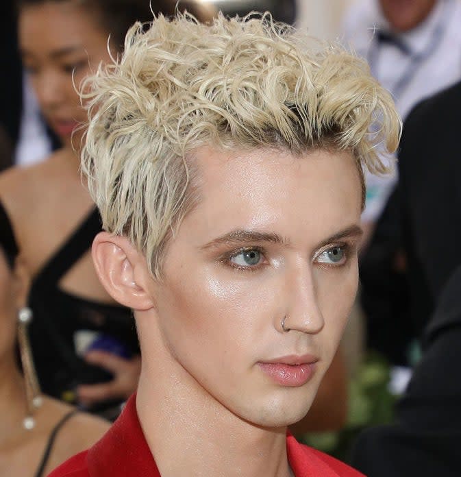 Troye with nose ring, wearing bold blazer over sheer top