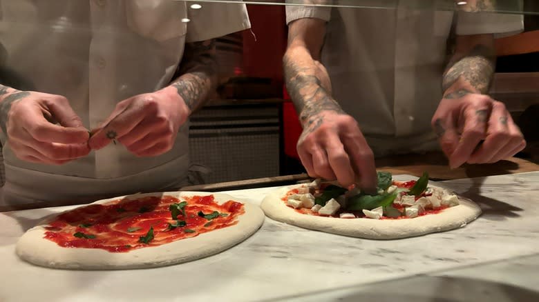 Chefs topping pizzas