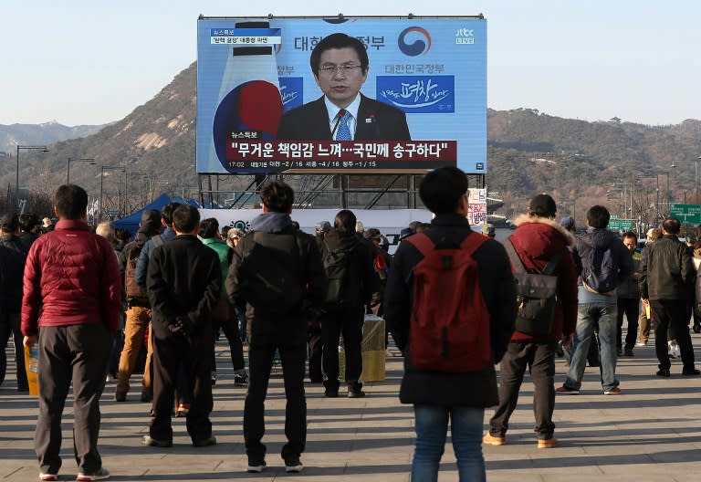 People watch a live broadcast showing South Korea's Acting President and Prime Minister Hwang Kyo-Ahn delivering a public address in Seoul on March 10, 2017