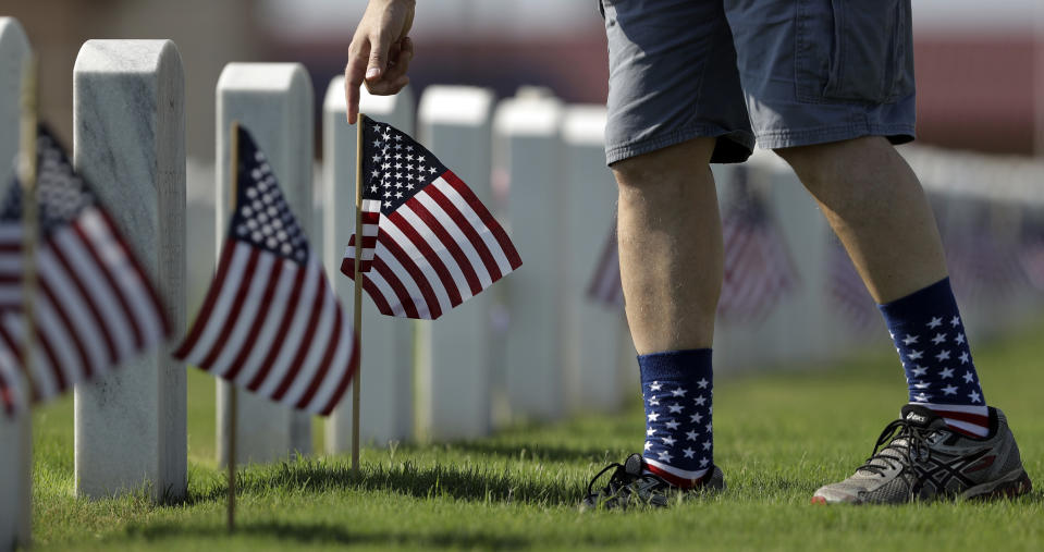 <p>A volunteer helps place some of the more than 100,000 U.S. flags next to headstones at Fort Sam Houston National Cemetery in preparation of Memorial Day, Friday, May 25, 2018, in San Antonio, Texas. (Photo: Eric Gay/AP) </p>