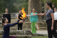 Greek actress Xanthi Georgiou, right, playing the role of the High Priestess, lights the torch during the final rehearsal for the lighting of the Olympic flame at Ancient Olympia site, birthplace of the ancient Olympics in southwestern Greece, Sunday, Oct. 17, 2021. The flame will be transported by torch relay to Beijing, China, which will host the Feb. 4-20, 2022 Winter Olympics. (AP Photo/Thanassis Stavrakis)