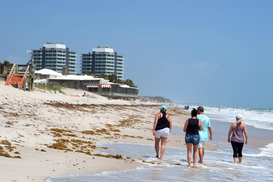 Beach-goers walk along the waterline on Friday, May 15, 2020, in front of Costa d'Este Beach Resort & Spa in Vero Beach. Local hotels saw drastically lower reservations in the wake of the coronavirus pandemic. The beach resort, co-owned by singer Gloria Estefan, re-opened May 8.