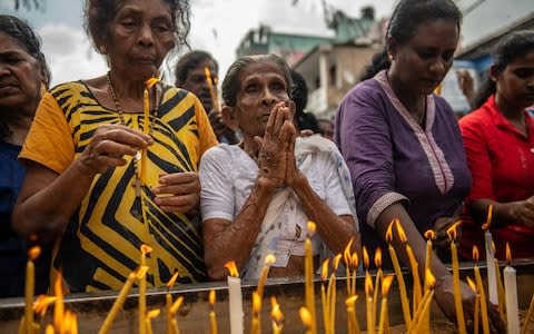 Women light candles as they pray in the street near St Anthony's Shrine - Credit: Carl Court