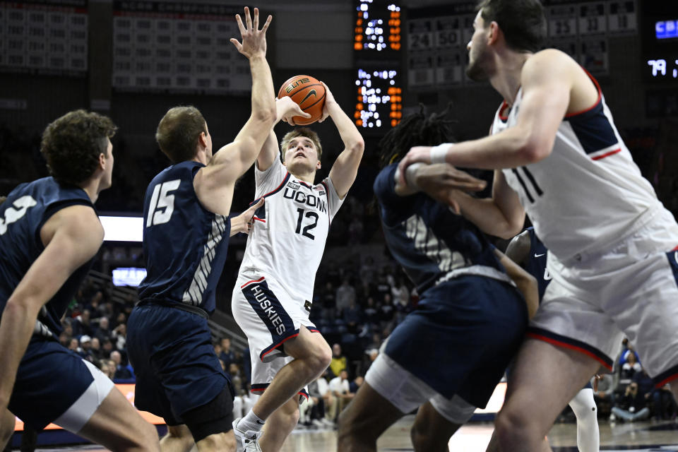 UConn guard Cam Spencer (12) looks to shoot over New Hampshire forward Davide Poser (15) in the second half of an NCAA college basketball game, Monday, Nov. 27, 2023, in Storrs, Conn. (AP Photo/Jessica Hill)