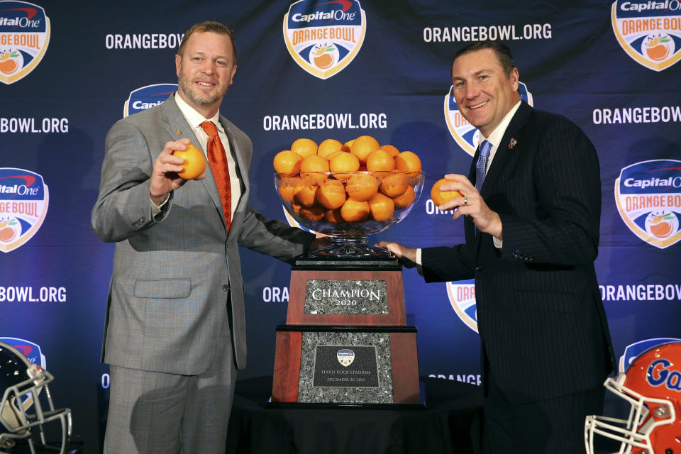 Virginia Cavaliers head coach Bronco Mendenhall, left, and Florida Gators head coach Dan Mullen, right, pose for a photograph during a news conference for the Orange Bowl NCAA college football game, Sunday, Dec. 29, 2019, in Fort Lauderdale, Fla. Florida plays Virginia in the Orange Bowl on Dec. 30. (AP Photo/Mario Houben)