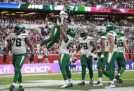 New York Jets running back Michael Carter (32), top center, celebrates after scoring a touchdown during the second half of an NFL football game between the New York Jets and the Atlanta Falcons at the Tottenham Hotspur stadium in London, England, Sunday, Oct. 10, 2021. (AP Photo/Ian Walton)