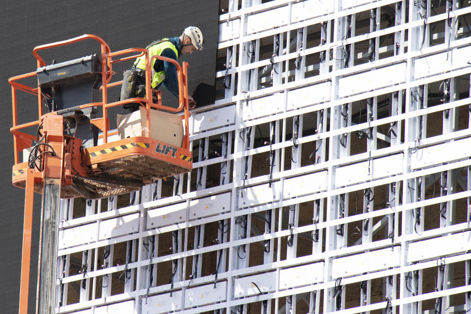 cladding  Construction worker in crane basket installing sheets cladding for covering metal structure on a building facade wall