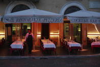 FILE - In this Friday, March 6, 2020 filer, a waiter waits for customers in front of a restaurant in Navona square in Rome. The focal point of the coronavirus emergency in Europe, Italy, is also the region's weakest economy and is taking an almighty hit as foreigners stop visiting its cultural treasures or buying its prized artisanal products, from fashion to food to design. Europe’s third-largest economy has long been among the slowest growing in the region and is the one that is tallying the largest number of virus infections outside Asia. (AP Photo/Andrew Medichini, File)