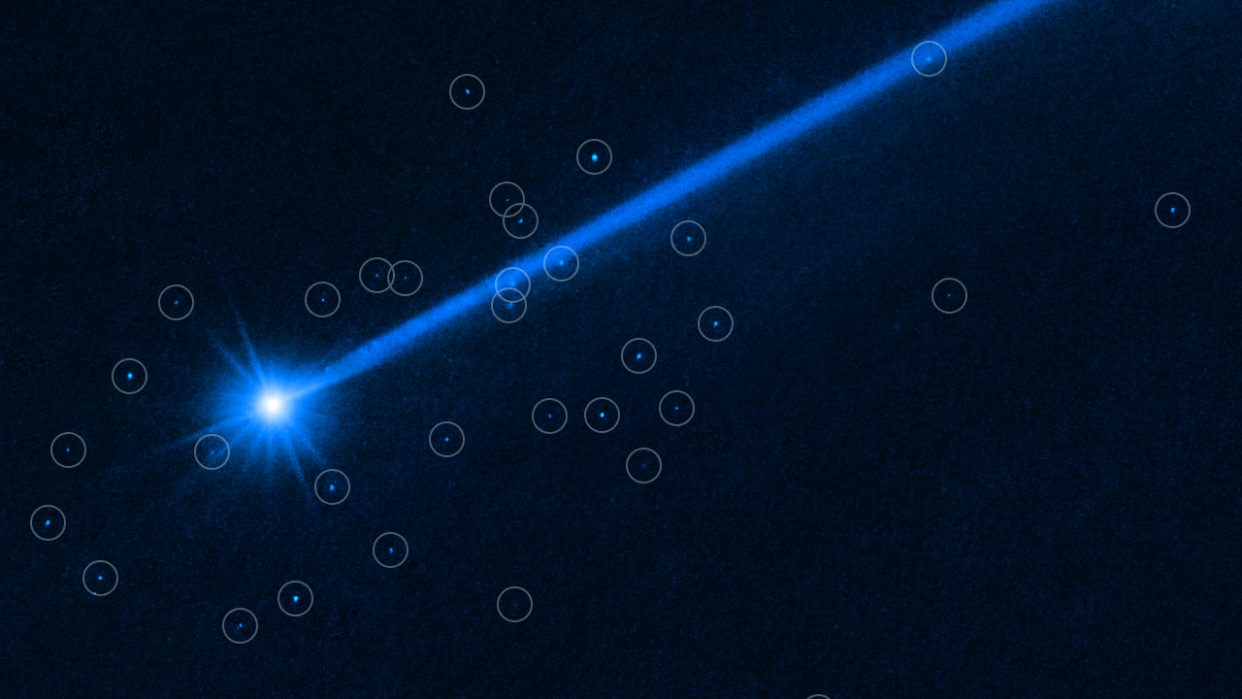  A streak of blue glowing light is shown against a dark background of space. Around the streak are spots representing the boulders, each one circled to highlight the positions.  