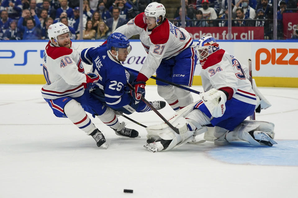 Montreal Canadiens defenseman Alexander Romanov (27) checks Toronto Maple Leafs forward Ondrej Kase (25) against Canadiens' Joel Armia (40) during the second period of an NHL hockey game Wednesday, Oct. 13, 2021, in Toronto. (Evan Buhler/The Canadian Press via AP)