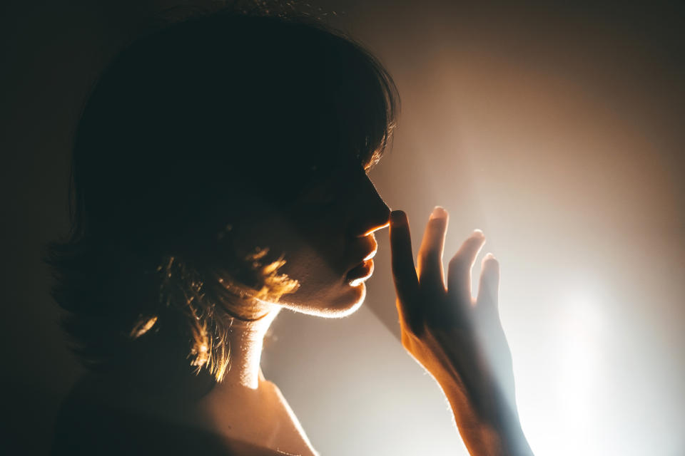 Silhouette of a person in profile with hand near face against a light background