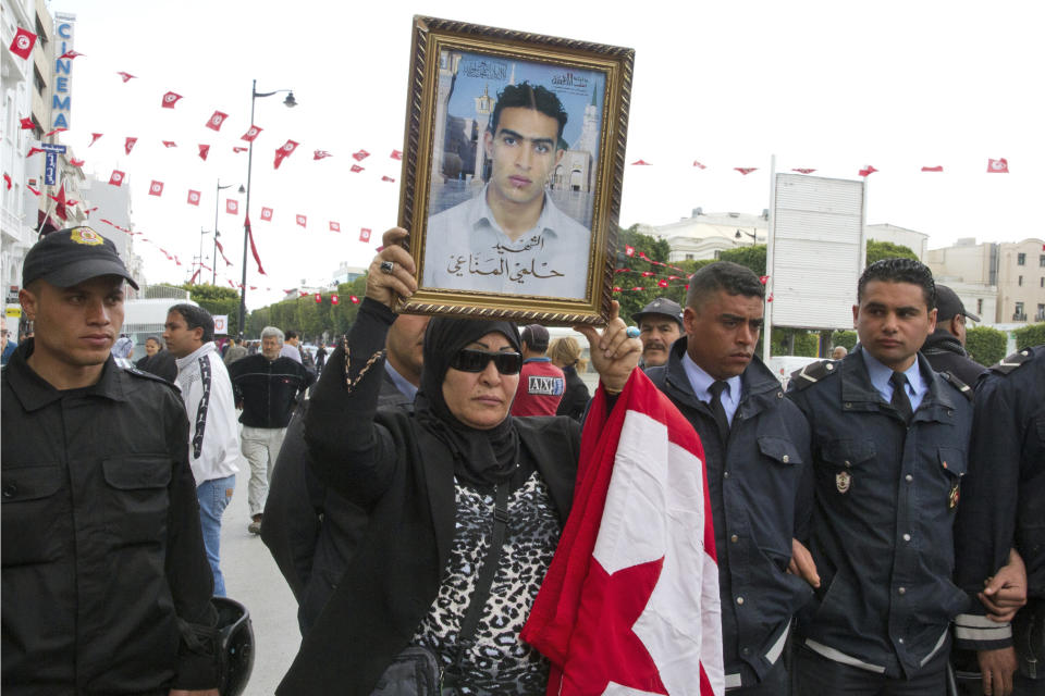 FILE - In this April 9, 2012 file photo, a Tunisian woman holds a poster of her martyr son named Helmi Manaai, written under the photo, during a protest in Tunis. Since winning a parliamentary seat in 2019, Tunisian lawmaker Abir Moussi has become one of the country’s most popular, and most controversial, politicians, riding a wave of nostalgia for a more stable and prosperous time, just as Tunisia marks 10 years since protesters overthrew autocratic former President Zine El Abidine Ben Ali. Since 2011, Tunisia has been plagued by sinking wages, growing joblessness and worsening public services. Unemployment has risen amid the coronavirus pandemic from 15% to 18%. Attempts to migrate to Europe by sea have soared. (AP Photo/Amine Landoulsi, File)