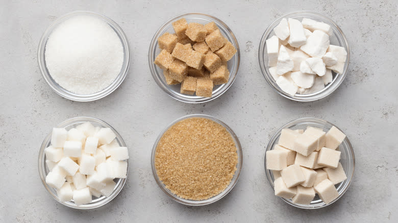 Six glass dishes of sugar cubes and granules