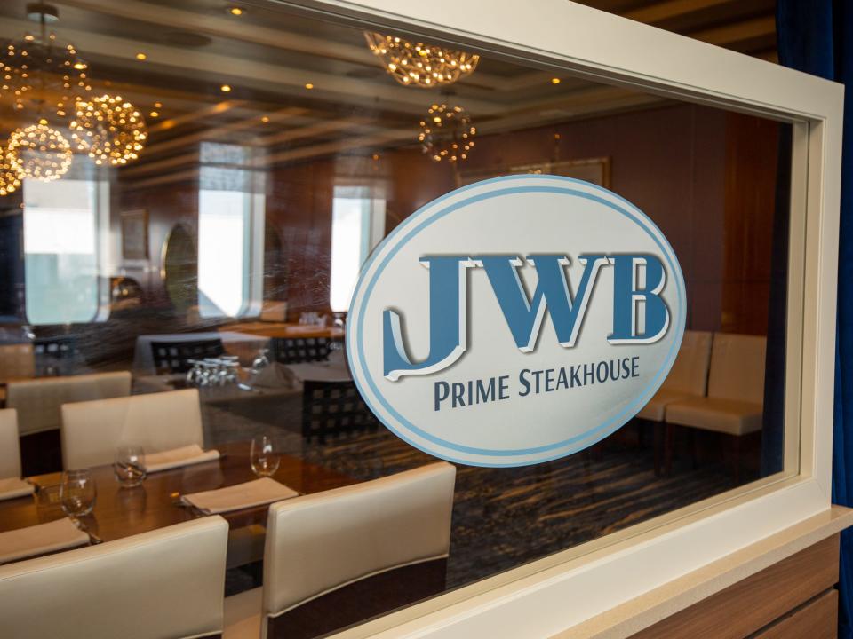 A glass panel that says "JWB prime steakhouse" with tables in the back.