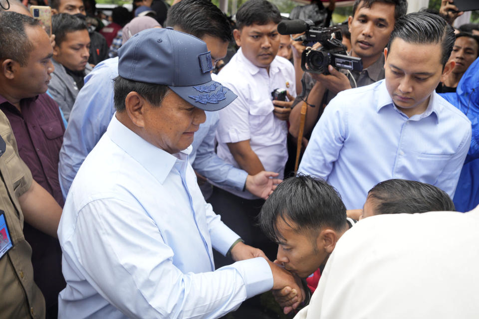 A supporter kisses the hand of Indonesian presidential candidate Prabowo Subianto after he voted during the election in Bojong Koneng, Indonesia, Wednesday, Feb. 14, 2024. Indonesian voters were choosing a new president Wednesday as the world's third-largest democracy aspires to become a global economic powerhouse a quarter-century after shaking off a brutal dictatorship. (AP Photo/Vincent Thian)