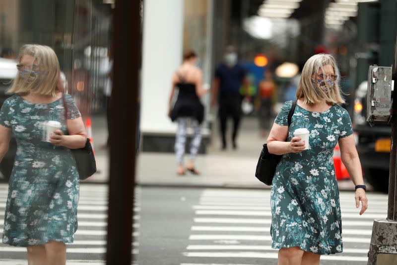 Pedestrians wearing masks walk down the sidewalk in the Manhattan borough of New York City