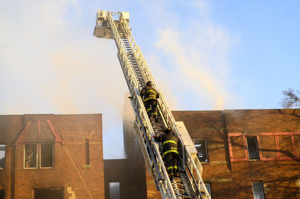 Detroit firefighters climb an aerial ladder to battle a large fire in Detroit, Friday, April 7, 2023. About a dozen people have been hurt in an early morning apartment building fire on Detroit's westside. (Andy Morrison /Detroit News via AP)