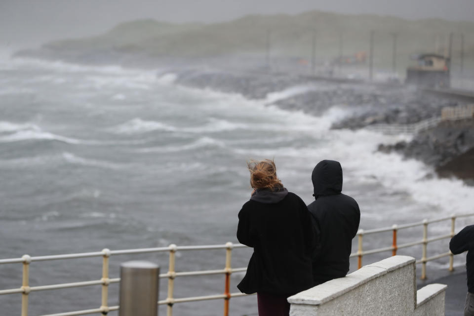 People watch the waves and sea spray at Lahinch in County Clare on the West Coast of Ireland.