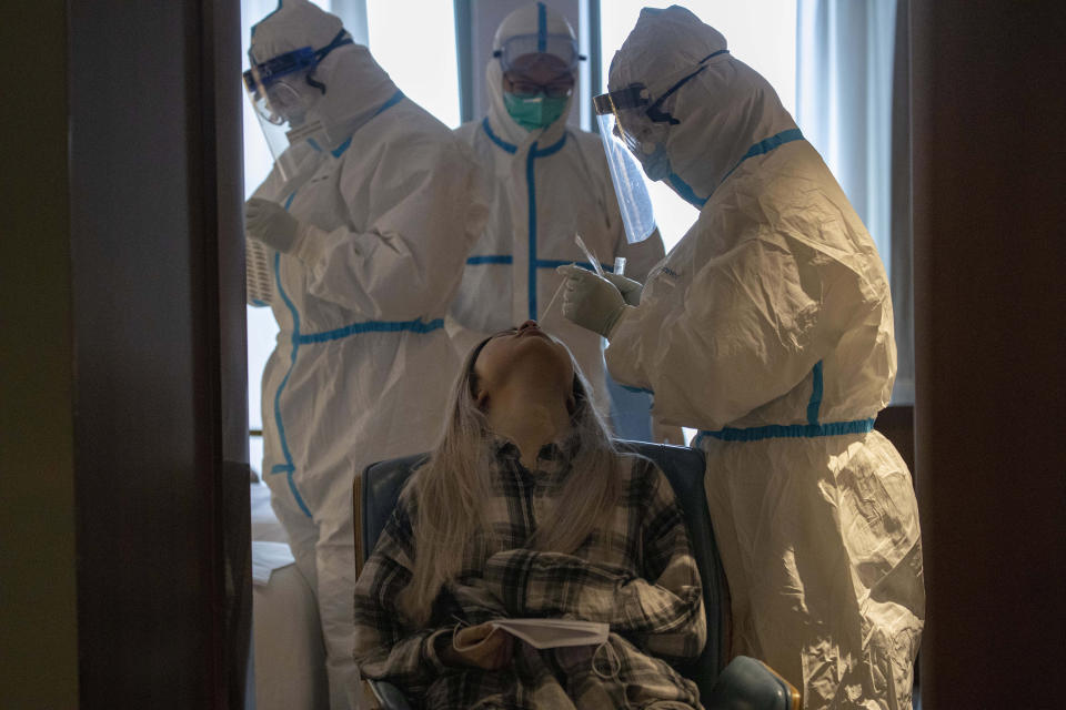 A woman takes a COVID-19 test at a quarantine hotel in Wuhan in central China's Hubei province on Tuesday, March 31, 2020. China on Tuesday reported just one new death from the coronavirus and a few dozen new cases, claiming that all new cases came from overseas. (AP Photo/Ng Han Guan)