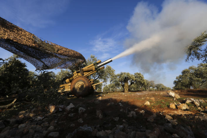 Turkish backed rebel fighters fire a howitzer toward Syrian government's forces positions near the village of Neirab in Idlib province, Syria, Thursday, Feb. 20, 2020. Two Turkish soldiers were killed Thursday by an airstrike in northwestern Syria, according to Turkey's Defense Ministry, following a large-scale attack by Ankara-backed opposition forces that targeted Syrian government troops. (AP Photo/Ghaith Alsayed)