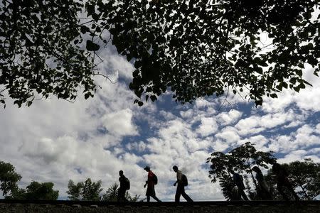 Immigrants walk toward the premises of a group called "Las Patronas" (The bosses), a charitable organization that feeds Central American immigrants on their way to the border with the United States who travel atop a freight train known as "La Bestia", in Amatlan de los Reyes, in Veracruz state, Mexico October 22, 2016. REUTERS/Daniel Becerril