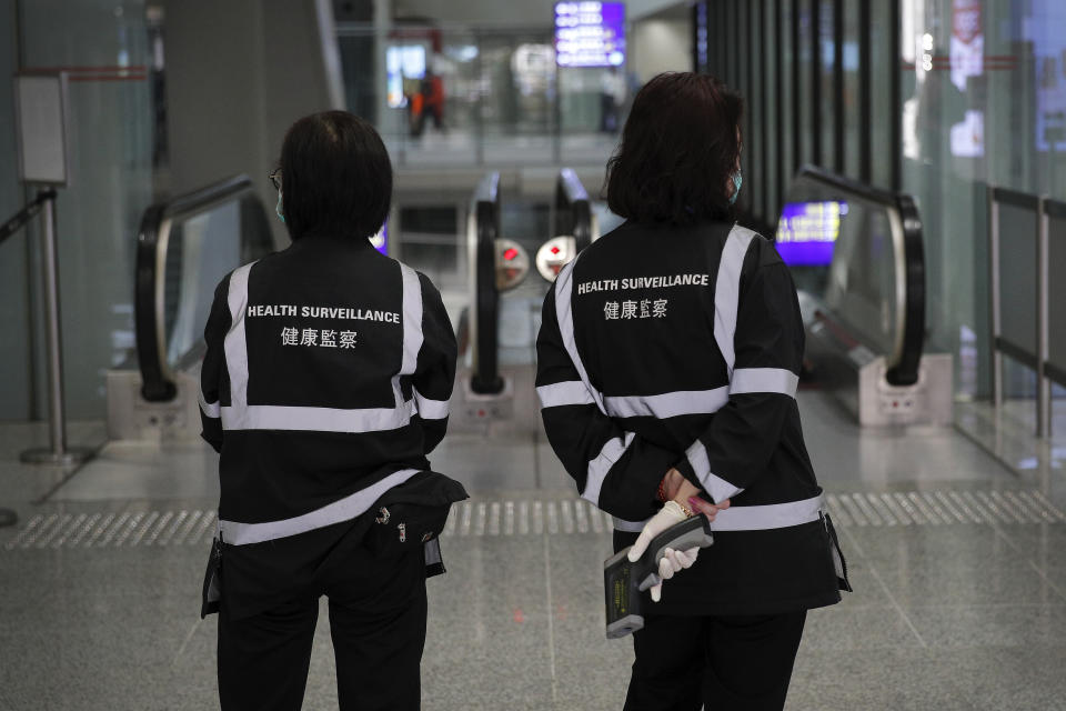 A health surveillance officer with temperature scanner waits for passengers at the Hong Kong International airport in Hong Kong, Saturday, Jan. 4, 2020. Hong Kong authorities activated a newly created "serious response" level Saturday as fears spread about a mysterious infectious disease that may have been brought back by visitors to a mainland Chinese city. (AP Photo/Andy Wong)