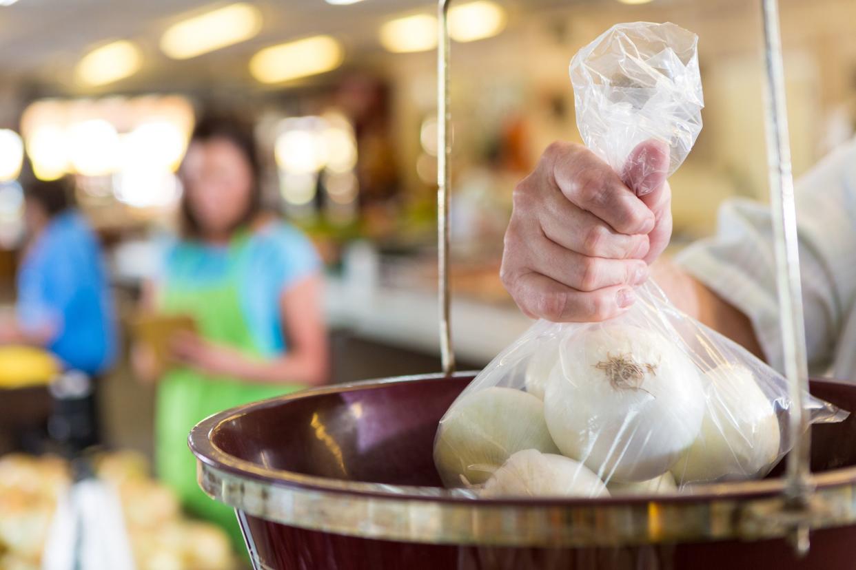 customer weighing bag of onions in grocery store produce aisle