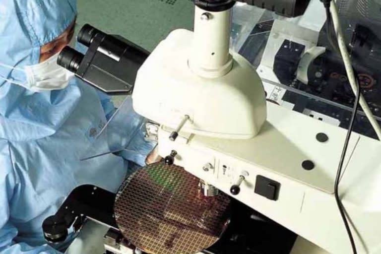 Un operario de la firma TSMC, en Taiwán, observa bajo el microscopio un waffer. Estas obleas son una de las últimas etapas de la fabricación de los chips. TSMC está operando al 100% y aun así no da abasto